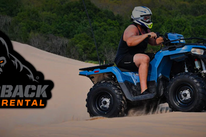 a man riding a motorcycle down a dirt road